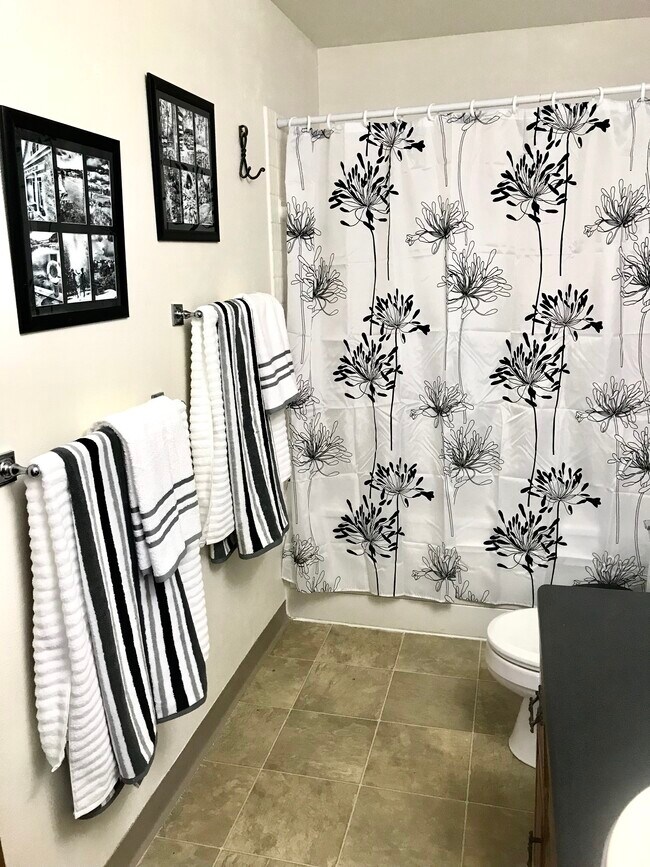 Baño con bañera completa, remodelación reciente, piso de baldosas, encimera y lavabo renovados, diseño fresco. - 502 Crab Apple Court