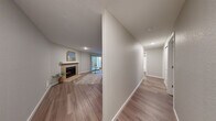 Located at 14820 Redmond Way in Redmond, WA, this two-bedroom, two-bathroom single-floor residence offers a well-organized layout with consistent wood-style flooring flowing throughout. The living room serves as a central gathering space, anchored by a tile-surround fireplace with a clean white mantle and access to a sliding glass door that brings in natural light. Adjacent, the dining area features a ceiling fan and connects seamlessly to the galley-style kitchen, which is outfitted with stainless steel appliances including a gas range, refrigerator, and dishwasher, complemented by two-tone cabinetry — white uppers and warm gray lowers — with quartz countertops and a subway tile backsplash. A hallway leads to both bedrooms, each finished with the same wood-style flooring and neutral wall tones. The spacious primary bedroom includes a sliding closet and natural light from a window. The second bedroom offers a similarly bright and clean feel. Both bathrooms are finished with modern dark-wood vanities, quartz countertops, and textured walls. The overall aesthetic is clean, neutral, and move-in ready, making efficient use of the available space.