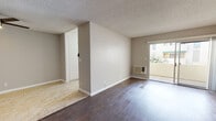 This single-floor residence offers a thoughtfully designed layout that balances open living areas with functional private spaces. The main living and dining areas are finished with rich, dark hardwood flooring that extends throughout much of the unit, complemented by neutral gray walls and white trim that create a clean, contemporary aesthetic. Textured ceilings add a classic touch, while a ceiling fan in the dining area provides comfort and airflow.

The galley-style kitchen is efficiently arranged with white cabinetry, a stainless steel refrigerator, a white electric range, and light stone-tiled flooring — providing a practical workspace that connects seamlessly to the dining area. A wall-mounted A/C unit services the living space, which opens toward a private outdoor area with natural light streaming in.

The bedrooms are spacious and feature the same dark hardwood flooring. The primary bedroom is notably generous, with two separate closets offering ample storage. Additional bedrooms include wall-mounted A/C units and windows that invite natural light.

The bathrooms are finished with warm beige tile flooring. One bathroom features a framed mirror, a modern gray vanity with a white quartz countertop, and a window for natural light. The second bathroom includes a tub-shower combination with a glass enclosure. Together, these spaces present a move-in ready home with practical finishes throughout.
