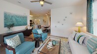 Located at 4000 Coleway Dr in Holly Springs, NC, this single-floor residence offers a well-designed, open-concept layout with modern finishes and a cohesive aesthetic throughout. The living area is bright and welcoming, featuring wood-look flooring, a ceiling fan, and French doors that fill the space with natural light and provide access to the outdoors. The open flow connects the living room seamlessly to a dedicated dining area and kitchen, making it ideal for everyday living and entertaining. The kitchen is appointed with granite countertops, white cabinetry with sleek bar-pull hardware, stainless steel appliances including a gas range, microwave, and refrigerator, a tile backsplash, and a large single-basin undermount sink set into a generous island with pendant lighting overhead. A pantry adds convenient storage. The bedrooms offer plush carpeting, ceiling fans, and ample space, with the primary suite featuring direct access to an en-suite bathroom. The bathrooms are finished with granite-topped white vanities, wood-look flooring, and tub/shower combinations. The clean, neutral palette and consistent design language create a cohesive and comfortable living environment throughout this thoughtfully laid-out home.