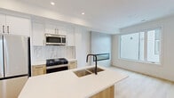 This contemporary townhouse in Calgary offers a well-designed living space across two floors, totaling 770 square feet. The ground floor spans 390 square feet, while the upper level provides 380 square feet of living area. The property boasts two bedrooms, including a primary bedroom of 110 square feet, and two full bathrooms.

The interior showcases a modern aesthetic with clean lines and a neutral color palette. Light wood flooring runs throughout, complementing the crisp white walls and creating a bright, airy atmosphere. Large windows in the bedrooms and living areas allow for ample natural light and offer views of the surrounding neighborhood.

The kitchen is a standout feature, equipped with stainless steel appliances, including a refrigerator, stove, and built-in microwave. White cabinetry extends to the ceiling, maximizing storage space, while a light-colored backsplash adds a touch of elegance. A kitchen island with a sink provides additional counter space and casual seating.

Both bathrooms exhibit a contemporary design with floating vanities, large mirrors, and glass-enclosed showers. The minimalist fixtures and hardware in matte black finish add a sophisticated touch to these spaces.

Throughout the home, recessed lighting and strategically placed windows contribute to the overall bright and open feel. The property's efficient layout and modern amenities make it an ideal choice for those seeking a stylish urban living experience in Calgary.
