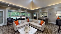 Located at 142 BPW Club Road in Chapel Hill, NC, this well-appointed single-floor clubhouse is designed to serve as a refined community gathering and amenity space. The main lounge area is a standout feature, showcasing soaring vaulted ceilings with elegant cove lighting that creates a warm, inviting ambiance. A white-tiled fireplace with a mounted flat-screen TV anchors one end of the room, while a generously sized sectional sofa, patterned area rug, and marble-top coffee table complete the stylish seating arrangement. Large sliding glass panels along one wall open seamlessly to a covered outdoor patio and pool deck, allowing abundant natural light to fill the interior and offering unobstructed views of the surrounding landscape and pool area.

Adjacent to the lounge is a functional kitchenette equipped with white cabinetry, dark countertops, stainless steel appliances, and a bar-height counter with seating — ideal for hosting events or casual gatherings. The fitness center occupies a dedicated room featuring rubber flooring, a cable machine system, a dumbbell rack, a spin bike, ceiling fan, full-length mirrors, and recessed lighting, providing a comprehensive workout environment. Together, these spaces deliver a cohesive, modern, and functional community facility.