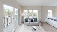Located at 8512 20th Ave NE in Seattle's vibrant Wedgwood neighborhood, this single-floor unit offers a thoughtfully designed open-concept layout bathed in natural light. The living area is a standout feature, anchored by an expansive wall of windows and a sliding glass door that opens to a private balcony overlooking the surrounding streetscape and lush tree canopy. Light-toned hardwood-style flooring runs throughout, complementing the clean, neutral wall palette and lending the space a bright, airy feel. A dedicated dining nook sits adjacent to the living area, framed by large windows that bring in generous daylight and neighborhood views, making it an inviting spot for everyday meals. The kitchen is efficiently designed with dark-toned cabinetry, light countertops, a stainless steel sink, and built-in appliances, providing a functional and contemporary cooking environment. The bedroom is a peaceful retreat, featuring a large window that fills the room with natural light, while maintaining a calm, restful atmosphere. The overall design reflects a modern aesthetic with clean lines, contemporary finishes, and a cohesive color scheme throughout. Its elevated position offers pleasant views and a sense of connection to the neighborhood, making this a well-appointed urban residence in the heart of Seattle.