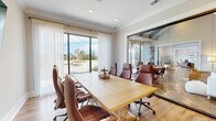 Located in Daytona Beach, FL, this single-story business center offers a polished and functional environment designed to support professional productivity. The centerpiece of the space is a spacious conference room anchored by a solid wood conference table surrounded by high-back leather executive chairs. Crown molding and recessed lighting add a refined finish to the room, while large floor-to-ceiling sliding glass doors dressed with sheer white curtains flood the space with natural light and provide views of the landscaped exterior.

A wall-mounted flat-screen display serves as a focal point for presentations, complemented by a dedicated workstation area along one wall. Decorative touches, including a world map wall art piece, contribute to the professional yet welcoming atmosphere.

Full-height glass panel partitions separate the conference room from an adjacent collaborative area, maintaining visual connectivity while offering acoustic separation. Through the glass, a lounge area with comfortable seating and a dining space with vaulted ceilings are visible, reflecting a thoughtfully designed, multi-functional environment. Warm hardwood flooring runs throughout, unifying the space with a consistent and contemporary aesthetic well-suited for meetings, focused work, and team collaboration.