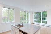 Located at 339 Garden Street in South Burlington, Vermont, this thoughtfully designed 2-bedroom, 2-bathroom residence offers a clean, contemporary aesthetic throughout its efficiently utilized single-floor layout. Light hardwood flooring flows seamlessly across all rooms, complementing the bright white walls and recessed lighting that give the space an open, airy feel.

The kitchen serves as a central hub, featuring a large island with a stainless steel sink, laminate countertops, white shaker-style cabinetry, and a full suite of stainless steel appliances including a refrigerator, range, microwave, and dishwasher. An abundance of large windows surrounds the kitchen and living area, framing lush, tree-lined views and flooding the space with natural light.

The primary bedroom is a comfortable, well-proportioned room with a large picture window overlooking the greenery outside and a dedicated closet. The second bedroom is bright and versatile, also featuring a window with outdoor views. Three closets throughout the unit provide ample storage.

Both bathrooms maintain the home's clean design language, featuring white vanities, light wood-tone flooring, and tub-shower combinations. An in-unit laundry area adds everyday convenience. The overall ambiance is modern, bright, and move-in ready.