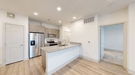 This well-designed two-story residence offers 2 bedrooms and 1 bathroom across a thoughtfully laid-out floor plan. The main level centers around an open-concept kitchen and living area, finished with light hardwood flooring and recessed lighting that creates a bright, welcoming atmosphere. The kitchen is a standout feature, boasting a large peninsula with granite countertops and an integrated sink, complemented by taupe cabinetry, stainless steel appliances including a French door refrigerator, electric range, and microwave. A glass-panel exterior door allows natural light to flow into the living space. Carpeted stairs with a railing lead to the upper level, where both bedrooms are located. Each bedroom features soft carpet flooring, a ceiling fan, and windows with blinds that invite natural light. The primary bedroom is a comfortable, well-proportioned retreat. The shared full bathroom on the upper level is finished with light hardwood flooring, a granite-topped vanity with taupe cabinetry, and a tub-shower combo with white tile surround. A dedicated closet on the upper floor provides additional storage. Clean white walls and consistent finishes throughout give the space a cohesive, modern aesthetic.