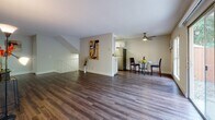 This single-floor residence offers a thoughtfully designed layout that balances open living spaces with functional private areas. Rich, dark hardwood-style flooring runs throughout, providing a cohesive and polished look from room to room.

The main living area is generously proportioned, featuring a textured ceiling and large sliding glass doors that flood the space with natural light while offering direct views of lush, mature greenery outdoors. The open flow connects seamlessly to a dedicated dining area, which is accented by a ceiling fan and sits adjacent to the kitchen.

The kitchen is well-equipped with white shaker-style cabinetry, white quartz countertops, and a full suite of stainless steel appliances including a gas range, microwave, and refrigerator. A skylight adds additional brightness to the workspace.

The bedrooms are bright and comfortable, each featuring hardwood-style flooring and ample closet space, including mirrored sliding-door closets in one room. Windows in the bedrooms frame views of the surrounding landscape, enhancing the sense of connection to the outdoors.

The bathroom is cleanly finished with white cabinetry, a vessel sink, quartz countertop, and a full tub-and-shower combination with tile surround. Throughout the residence, neutral tones and clean lines create a calm, inviting ambiance.