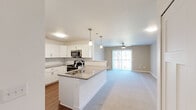 This well-designed one-bedroom, one-bathroom residence at 332 Brookhill Dr in Athens, Alabama offers a thoughtfully organized single-floor layout. The open-concept living and kitchen area creates a seamless flow, anchored by a peninsula with a quartz-style countertop, undermount sink, and stylish pendant lighting. The kitchen is equipped with stainless steel appliances—including a refrigerator, range, and over-the-range microwave—complemented by crisp white shaker cabinetry and a classic subway tile backsplash. Wood-look flooring runs throughout the kitchen, transitioning to plush carpet in the living area and bedroom. The living room is bright and inviting, featuring a ceiling fan and a sliding glass door that fills the space with natural light and outdoor views. The generously sized primary bedroom includes its own ceiling fan, a window with outdoor views, and direct access to additional storage. The bathroom is finished with a backlit vanity mirror, grey countertop, white cabinetry, and wood-look flooring, offering a clean and modern aesthetic. Clean lines, neutral tones, and contemporary finishes throughout give this residence a cohesive, move-in-ready appeal.
