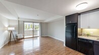 Located at 2895 Pauling Ave in Richland, WA, this one-bedroom, one-bathroom unit offers a well-organized single-floor layout. The open-concept living and kitchen area is anchored by warm hardwood-style flooring that runs throughout the main living spaces. The kitchen features dark lower cabinetry paired with white upper cabinets, granite-style countertops, and black appliances including a refrigerator, range, and microwave — all set against a bright, clean backdrop. The living area is generously proportioned, with neutral-toned walls and a sliding glass door that opens to a private balcony, allowing abundant natural light and outdoor views to fill the space. The bedroom is carpeted for comfort and includes a window with blinds that frame views of surrounding greenery, contributing to a calm and quiet atmosphere. A dedicated closet provides practical storage. The bathroom features hardwood-style flooring, a dark vanity with a granite-style countertop, a mirrored medicine cabinet, and a bold panel door that adds a modern, contemporary touch. Throughout the unit, dark-finish doors contrast with light walls, creating a cohesive and stylish aesthetic that balances modern design with everyday functionality.