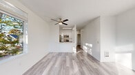 Located at 255 W Broadway in the heart of Eugene, Oregon, this thoughtfully designed two-bedroom, two-bathroom residence offers a clean, modern aesthetic throughout its single-floor layout. Light gray wood-look flooring flows seamlessly across every room, complementing the crisp white walls and creating a bright, airy atmosphere. The open living area is anchored by a ceiling fan and benefits from abundant natural light, with generous windows that frame views of the surrounding neighborhood's mature trees and urban streetscape. The kitchen is a standout feature, boasting a galley-style layout with two-tone cabinetry — white uppers paired with gray lowers — white quartz countertops, a stainless steel sink, and a full suite of stainless steel appliances including a refrigerator, range, microwave, and dishwasher. A pass-through peninsula connects the kitchen to the living space, enhancing the open feel. Both bedrooms are well-proportioned and sun-drenched, with the primary bedroom offering comfortable scale and a sliding-door closet. The bathrooms are clean and functional, featuring a full tub-shower combo with brushed gold fixtures. A dedicated in-unit laundry room with a full-size washer and dryer adds everyday convenience. Recessed lighting and gold-toned hardware accents lend the space a polished, contemporary finish throughout.
