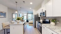 Located at 11750 Alliance Circle in Chester, VA, this 1-bedroom, 1-bathroom residence offers a thoughtfully designed open-concept floor plan that maximizes every square foot. Light wood-style flooring flows throughout the space, creating a cohesive and airy feel.

The kitchen is a standout feature, boasting white shaker cabinetry with matte black hardware, granite-style countertops, a herringbone tile backsplash, and a full suite of stainless steel appliances including a range, microwave, refrigerator, and dishwasher. A kitchen island provides additional prep and dining space, while pendant lighting adds a polished finishing touch.

The open living room benefits from large windows and a glass door that invite generous natural light and outdoor views. A ceiling fan and a calming blue-gray accent wall give the space a relaxed yet refined character.

The bedroom is a comfortable retreat, featuring a ceiling fan, large windows with scenic outdoor views, and easy access to a dedicated closet with built-in storage. The full bathroom includes a tub-shower combination with clean white tile finishes and light wood-style flooring.

The entryway is clean and functional, with direct access to the main living areas. Throughout, the design maintains a bright, neutral palette that feels modern and welcoming.