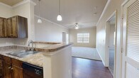 This single-story, 2-bedroom, 2-bathroom residence offers a thoughtfully designed layout that maximizes functionality and comfort. The open-concept living area seamlessly connects the kitchen, dining, and living room, creating an inviting communal space. The kitchen features rich, dark wood cabinetry, granite-style countertops, a double stainless steel sink, and black appliances including a refrigerator, range, and built-in microwave. Pendant lighting over the peninsula and crown molding add a refined touch, while hardwood-style flooring grounds the space. The living area is finished with plush carpet, a ceiling fan, and a window that fills the room with natural light.

Both bedrooms are generously sized, featuring soft carpet flooring, ceiling fans, and windows with blinds. The primary bedroom includes a spacious walk-in closet with dual hanging rods for ample storage. The two bathrooms are finished with tile flooring, granite-style vanity countertops, and dark wood cabinetry. One bathroom features a separate soaking tub and a glass-enclosed shower, while the other offers a tub-shower combination. Additional highlights include five closets, a pantry, a dedicated laundry area, and a utility room, ensuring abundant storage throughout.