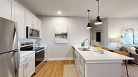 Located at 91 Kaiman Ln in Valley Park, Missouri, this single-floor residence offers a thoughtfully designed open-concept layout with modern finishes throughout. The kitchen is a standout feature, showcasing white shaker cabinetry, a white quartz waterfall island with bar seating for multiple guests, stainless steel appliances including a refrigerator, electric range, and built-in microwave, plus a white subway tile backsplash. Stylish matte black pendant lights illuminate the island, adding a contemporary touch. Light-toned luxury vinyl plank flooring flows seamlessly through the kitchen and into adjoining areas, while bold gray panel doors provide a striking design accent. The living area is bright and welcoming, with recessed lighting and a sliding glass door that invites natural light and provides outdoor access. The bedroom features neutral-toned walls, warm wood flooring, and a window that brings in additional natural light, creating a calm and restful retreat. The bathroom is cleanly appointed with gray cabinetry, white quartz countertops, and a tub-shower combination. Throughout the space, a consistent palette of soft grays, whites, and warm wood tones creates a cohesive and contemporary atmosphere well-suited for comfortable everyday living.