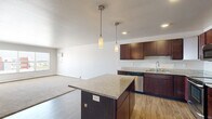 Located at 3915 54th St S in Fargo, North Dakota, this single-floor, 3-bedroom, 2-bathroom home offers a well-designed layout with a comfortable and functional living environment. The open-concept kitchen and living area serves as the heart of the home, showcasing rich dark cabinetry, granite countertops, a central island, pendant lighting, and a full suite of stainless steel appliances including a refrigerator, range, microwave, and dishwasher. Wood-style flooring runs throughout the kitchen, while the living area features plush carpeting and a large picture window that fills the space with natural light and offers views of the surrounding neighborhood. The three bedrooms are carpeted and well-proportioned, with the generously sized primary bedroom featuring a window with neighborhood views and baseboard heating. Both bathrooms are finished with stone-tile flooring and dark vanity cabinetry topped with granite counters; one bathroom includes a walk-in shower, while the other offers a tub/shower combination. A dedicated in-unit laundry room is equipped with a full-size washer and dryer and overhead shelving, adding everyday convenience. Neutral tones and clean finishes throughout give the home a move-in-ready appeal.