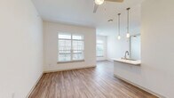 Located in the Grande Dunes North Village community in Longs, SC, this one-bedroom, one-bathroom residence offers a thoughtfully designed open-concept layout with modern finishes throughout. The combined kitchen and living area is anchored by wide-plank wood-look flooring, crisp white walls, and an abundance of natural light streaming through multiple large windows with views of the surrounding community. A ceiling fan adds comfort to the airy living space, which also features a glass door leading to outdoor access.

The kitchen is well-equipped with shaker-style cabinetry in a soft gray tone, white quartz countertops, a classic subway tile backsplash, and a full suite of stainless steel appliances including a refrigerator, range, microwave, and dishwasher. A peninsula with pendant lighting provides additional prep space and casual seating.

The bedroom is a comfortable retreat, featuring plush carpeting, a large window with outdoor views, and direct access to the bathroom. The bathroom connects to a dedicated walk-in closet outfitted with wire shelving for organized storage. The overall design is clean, bright, and contemporary, creating a functional and welcoming living environment.