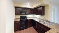This single-floor, 2-bedroom, 2-bathroom residence is thoughtfully designed to maximize comfort and functionality. Warm, neutral yellow-toned walls and recessed lighting create a bright and welcoming ambiance throughout the unit.

The open living and dining area features durable hardwood-style flooring and a layout that flows seamlessly into the kitchen. The kitchen is well-appointed with rich dark espresso cabinetry, granite-style countertops, a double stainless steel sink, and a full suite of black appliances including a range, microwave, refrigerator, and dishwasher.

Both bedrooms are carpeted for comfort and bathed in natural light from multiple windows. The primary bedroom is generously sized with two full closets featuring built-in shelving, offering excellent storage capacity. The second bedroom also provides a comfortable, well-lit space.

The two bathrooms mirror each other in style, each featuring dark wood vanities with granite-style countertops, large mirrors with overhead lighting, and hardwood-style flooring. One bathroom includes a walk-in shower, while the other offers a tub-shower combination. Natural light enters each bathroom through frosted windows, enhancing the clean, functional aesthetic throughout this well-appointed home.