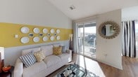 This single-floor residence is thoughtfully designed with a cohesive yellow, gray, and white color palette that carries throughout the space. The living room serves as a central focal point, showcasing dramatically vaulted ceilings, hardwood-style flooring, and a bold yellow horizontal accent stripe adorning the walls, complemented by decorative plate arrangements. A sliding glass door opens directly onto a private balcony, offering views of the surrounding neighborhood and filling the room with natural light.

The kitchen features light maple cabinetry, granite-style countertops, stainless steel appliances including a refrigerator, dishwasher, and microwave, along with a distinctive chalkboard backsplash. Track lighting overhead provides functional illumination, and the layout flows openly toward the living area.

Multiple bedrooms are carpeted and equipped with ceiling fans. The primary bedroom includes a walk-in closet, while additional bedrooms offer ample natural light through large windows with views of the exterior. Two full bathrooms include tub-shower combinations with tiled surrounds and large vanity mirrors, providing practical functionality throughout the residence.