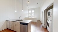 This contemporary two-story residence in Denver, CO offers three bedrooms and three bathrooms thoughtfully distributed across two floors. The open-concept kitchen is a standout feature, boasting light wood cabinetry, sleek gray quartz countertops, a full suite of stainless steel appliances including a refrigerator, range, microwave, and dishwasher, complemented by stylish pendant lighting and a white tile backsplash. Soaring ceilings amplify the sense of openness in the main living area, which features warm hardwood flooring that flows throughout. The upper floor transitions to plush carpeted bedrooms, each offering a ceiling fan and recessed lighting. The primary bedroom connects to a private en-suite bathroom equipped with a walk-in glass shower, a wood-toned vanity with an undermount sink, and large-format tile flooring. A second full bathroom mirrors the refined finishes, featuring a soaking tub with white subway tile surround. Two dedicated closets provide ample storage, including a walk-in closet with wire shelving. Clean white walls and neutral tones throughout create a bright, modern ambiance, making this Denver residence a well-designed and functional home.
