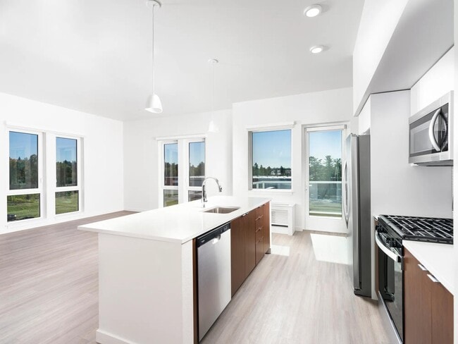 This open-concept apartment features a chef-ready kitchen with a gas range, sleek stainless steel appliances, and airy living spaces. - Modera Raleigh Hills