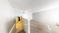 Located at 7110 W Central Ave in Wichita, Kansas, this single-floor home offers three bedrooms, two bathrooms, and a practical layout designed for comfortable everyday living. Textured ceilings are found throughout, complemented by neutral gray walls and a mix of warm carpet and light tile flooring that transitions between living and functional areas. A staircase with a railed landing opens to a carpeted living area bathed in natural light from window blinds, creating a bright and welcoming atmosphere. The kitchen is equipped with gray shaker-style cabinetry, light countertops with a subtle marble appearance, and a stainless steel dishwasher, offering both style and functionality. The spacious primary bedroom includes a built-in closet with shelving and receives ample natural light through a large window. The additional bedrooms also feature carpet flooring, neutral tones, and windows that invite natural light. The two bathrooms are well-appointed; one includes a full tub-shower combination with a clean white surround, while the other features a wide vanity with gray cabinetry, a light countertop, tile flooring, and a well-lit mirror. A hallway and two closets round out the layout, providing organized storage throughout this efficiently designed Wichita home.