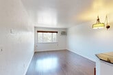 Located at 4550 E Jewell Ave in Denver, Colorado, this one-bedroom, one-bathroom unit offers a practical and well-organized layout across a single floor. Dark hardwood-style flooring runs throughout, providing a cohesive look that ties the rooms together.

The combined living and dining area forms the heart of the unit, offering an open feel with natural light streaming through a large window with wood-trimmed blinds. A wall-mounted air conditioning unit ensures year-round comfort. The kitchen is accessible via a half-wall breakfast bar, and features warm wood cabinetry with dark countertops.

The bedroom is a comfortable, well-proportioned space with its own window overlooking greenery outside, a wall-mounted AC unit, and a set of sliding panel closet doors offering ample storage. Additional closet space is distributed throughout the unit, with four closets in total.

The bathroom stands out with its fully tiled surround in large-format gray tiles, accented by a decorative mosaic border strip in black and metallic tones. A full soaking tub with shower completes the space.

A connecting hallway links the main living areas to the bedroom, maintaining a clear and functional flow throughout the unit. Clean white walls and consistent flooring contribute to a bright, neutral aesthetic throughout.