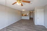 Located at 1704 Yonkers St in Plainview, Texas, this two-story home offers a clean, updated interior with a cohesive design throughout. The main level features an open-concept living area with light-toned luxury vinyl plank flooring that extends seamlessly through the space. A pass-through kitchen counter connects the living area to the kitchen, which is equipped with white cabinetry, warm wood-toned countertops, a matching backsplash, and white appliances including a range and refrigerator. A textured ceiling adds character to the main living spaces. Sliding glass doors in one of the main-level rooms flood the space with natural light and provide direct access to the outdoors, complemented by a ceiling fan overhead. The bathroom features a full tub-shower combination with classic white subway tile surround. Bedrooms are well-proportioned, featuring the same vinyl plank flooring, neutral gray walls, and windows fitted with blinds that allow for natural light. A staircase with a white-painted handrail leads to the upper floor, where additional rooms continue the home's consistent, understated aesthetic. Throughout, the home presents a move-in ready, functional layout suited for comfortable everyday living.