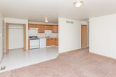 This single-floor unit at 2966 Beach Rd in Port Huron, Michigan, offers a straightforward and functional layout across several distinct areas. The kitchen is equipped with warm oak cabinetry, a white gas range, dishwasher, refrigerator, and a double sink, all complemented by a white tile backsplash and light ceramic tile flooring. A convenient closet sits adjacent to the kitchen area, providing additional storage. The kitchen opens naturally into the living area, where the flooring transitions to wall-to-wall carpet. The living space is generously sized and receives natural light through a large sliding glass door fitted with vertical blinds, which also provides access to an outdoor area. The bedrooms are carpeted and offer a calm, neutral atmosphere, each featuring windows with vertical blinds and dedicated closet space with bifold doors. The full bathroom includes a tiled floor, oak vanity with a white countertop, a combined tub and shower enclosed by sliding glass doors, and a toilet. Throughout the unit, warm wood tones and neutral wall colors create a consistent, understated aesthetic well-suited for everyday living.