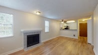 This single-floor residence offers a thoughtfully designed layout that balances open living spaces with comfortable private areas. The living room serves as the heart of the home, centered around a classic tile-surround fireplace with a clean white mantel. Light wood-style flooring extends throughout the main living areas, reflecting natural light that filters in through multiple windows dressed with white blinds. A textured ceiling and ceiling fan add both character and practicality to the space.

The kitchen is open to the living area via a pass-through counter with a dark countertop, creating a connected, social atmosphere. White shaker-style cabinetry provides ample storage, while stainless steel appliances — including a refrigerator, range, and dishwasher — offer modern functionality. The kitchen also features matching light wood-style flooring, maintaining visual continuity throughout.

The bedroom is a serene retreat, finished with soft neutral carpet and a baseboard heater beneath a window that brings in natural light. The full bathroom is clean and efficient, featuring a white vanity with modern hardware, a mirror, and a tub-shower combination with white tile surround. The space as a whole presents a cohesive, move-in-ready environment with a neutral palette throughout.
