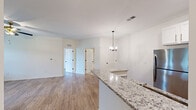 Located at 100 Foxborough Way in Richmond, Kentucky, this single-floor, 2-bedroom, 3-bathroom home offers a clean, modern design with thoughtful finishes throughout. The open-concept kitchen and living area serves as the heart of the home, featuring light hardwood flooring, a stylish chandelier, and an abundance of natural light from multiple windows. The kitchen is well-appointed with white shaker-style cabinetry accented by gold hardware, granite countertops with a mosaic tile backsplash, stainless steel appliances including a refrigerator, range, and dishwasher, and a peninsula that doubles as additional prep and dining space. The living room is bright and airy, with a ceiling fan, large windows, and direct access to an outdoor balcony. The bedrooms continue the light hardwood flooring aesthetic and are each equipped with ceiling fans. The primary bedroom includes an en-suite bathroom and a dedicated closet with wire shelving for organized storage. The bathrooms feature neutral tile flooring and clean, simple fixtures with matte black hardware accents. Throughout the home, arched interior doors and crisp white walls contribute to a fresh, contemporary ambiance that is both functional and inviting.