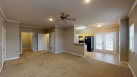 This single-floor residence offers a well-organized and functional layout designed for comfortable everyday living. The open-concept living area is spacious and filled with natural light, featuring plush wall-to-wall carpeting, crown molding, and a ceiling fan that enhances airflow and comfort. French doors at the rear of the living space provide a bright, welcoming connection to the outdoors. The kitchen is configured as a galley-style layout, outfitted with warm yellow cabinetry, granite-style countertops, a double-basin sink, black appliances including a range and refrigerator, and tile flooring. A breakfast bar peninsula separates the kitchen from the main living area, making it ideal for casual dining or entertaining. The bedrooms are generously sized, each featuring soft carpeting, ceiling fans, and windows that allow natural light to filter in. The bathroom includes a full soaking tub with a shower, built-in shelving, tile flooring, and a vanity with a granite-style countertop and well-lit mirror. Throughout the unit, warm taupe wall tones, white trim, and consistent finishes create a cohesive and inviting ambiance. Additional utility access is conveniently located within the unit.