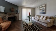 This single-floor home in Wichita, Kansas offers a well-organized layout with distinct living, dining, kitchen, bedroom, and bathroom spaces. The living room serves as the centerpiece of the home, highlighted by a striking brick fireplace with a raised hearth, rich hardwood flooring, a sliding glass door with vertical blinds that invites natural light, and a textured ceiling. The space flows naturally into a dedicated dining area featuring large-format tile flooring, a ceiling fan, and room for a full dining set. The galley-style kitchen is efficiently designed with gray cabinetry, butcher block countertops, a stainless steel sink, and tile flooring that continues from the dining area. The bedrooms are carpeted and include closet storage, with at least one bedroom featuring a walk-in closet with built-in shelving and hanging rods. Two bathrooms serve the home, each finished with light tile flooring and vanities with marble-style countertops — one includes a shower/tub combo. Throughout the home, neutral wall tones and consistent finishes create a cohesive and functional living environment suited for a variety of lifestyles.