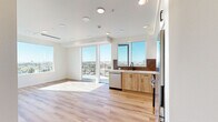 Located in San Diego's vibrant North Park neighborhood, this thoughtfully designed 3-bedroom, 2-bathroom residence offers a contemporary living experience with an open, airy feel. Light wood-tone flooring flows consistently throughout the entire space, unifying each room with warmth and continuity.

The open-concept living and kitchen area is bathed in natural light from large floor-to-ceiling windows and a sliding glass door that opens to a balcony, revealing sweeping elevated views of the San Diego cityscape. The kitchen is well-appointed with stainless steel appliances including a gas range, refrigerator, and dishwasher, complemented by a two-tone cabinetry design — white upper cabinets paired with natural wood lower cabinets — and a decorative penny-tile backsplash that adds texture and character.

Each of the three bedrooms features large windows that frame scenic city views, filling the rooms with abundant natural light. The primary bedroom includes a built-in closet with sliding doors. The two bathrooms share a consistent design language, each featuring warm wood vanity cabinetry, white quartz countertops, full-size soaking tubs with subway tile surrounds, and sleek matte black fixtures, creating a clean, modern aesthetic throughout.