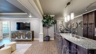 Located at 4101 SW Pointe Rd in Bentonville, Arkansas, this thoughtfully designed 2-bedroom, 2-bathroom single-floor residence offers a refined living experience with high-end finishes throughout. The open-concept layout seamlessly connects the living room, dining area, and kitchen, creating an inviting and functional space. The living room features a distinctive tray ceiling with crown molding, hardwood-style flooring, a ceiling fan, and access to natural light through exterior-facing windows and a door. The kitchen is outfitted with rich dark wood cabinetry reaching to the ceiling, granite countertops, a stylish tile backsplash, stainless steel appliances, and a breakfast bar with pendant lighting — ideal for both cooking and casual dining. The dining area flows naturally from the kitchen, complemented by hardwood-style flooring and decorative crown molding. Both bedrooms are generously sized, featuring plush carpeting, ceiling fans, and ample natural light. The spacious primary bedroom includes a dedicated closet and direct access to a well-appointed en-suite bathroom complete with a soaking tub, glass-enclosed walk-in shower, dual-sink granite vanity, and elegant tile flooring. The second bathroom mirrors the same quality with dark wood cabinetry and granite countertops. Crown molding, neutral tones, and architectural detailing tie the entire home together cohesively.