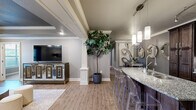 Located at 4101 SW Pointe Rd in Bentonville, Arkansas, this thoughtfully designed 2-bedroom, 2-bathroom single-floor residence offers a refined living experience with high-end finishes throughout. The open-concept layout seamlessly connects the living room, dining area, and kitchen, creating an inviting and functional space. The living room features a distinctive tray ceiling with crown molding, hardwood-style flooring, a ceiling fan, and access to natural light through exterior-facing windows and a door. The kitchen is outfitted with rich dark wood cabinetry reaching to the ceiling, granite countertops, a stylish tile backsplash, stainless steel appliances, and a breakfast bar with pendant lighting — ideal for both cooking and casual dining. The dining area flows naturally from the kitchen, complemented by hardwood-style flooring and decorative crown molding. Both bedrooms are generously sized, featuring plush carpeting, ceiling fans, and ample natural light. The spacious primary bedroom includes a dedicated closet and direct access to a well-appointed en-suite bathroom complete with a soaking tub, glass-enclosed walk-in shower, dual-sink granite vanity, and elegant tile flooring. The second bathroom mirrors the same quality with dark wood cabinetry and granite countertops. Crown molding, neutral tones, and architectural detailing tie the entire home together cohesively.