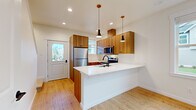 Located at 4228 Traverse Dr in Bellingham, WA, this two-story home offers 2 bedrooms and 3 bathrooms across two well-proportioned floors. The main level features an open-concept kitchen and living area with light hardwood flooring that enhances the bright, airy atmosphere. The kitchen is a standout, equipped with warm wood cabinetry, a white quartz peninsula with an undermount sink and matte black faucet, stainless steel appliances including a refrigerator, electric range, and over-the-range microwave, and pendant lighting overhead. A large window near the entry fills the living area with natural light and offers views of the surrounding neighborhood. The main level also includes a hallway and bathroom access. Upstairs, two carpeted bedrooms provide comfortable retreats, each with generous windows bringing in ample natural light. The primary bedroom includes a double-door closet and direct access to a bathroom. The bathrooms feature clean white tub-shower combinations with matte black fixtures, maintaining a cohesive modern aesthetic. A mini-split system provides climate control. The overall design is clean, contemporary, and functional, with consistent finishes throughout both floors.