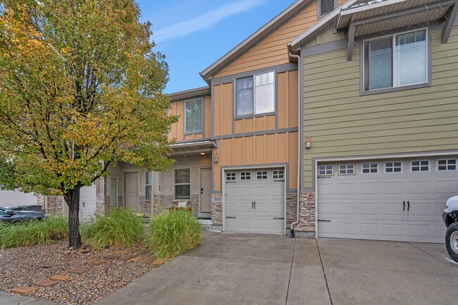 Warm-toned siding and stone facade, shrubs, and a tree greet you from the street - 10441 S Sage Vista Way