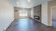 This single-floor, one-bedroom, one-bathroom unit offers a well-appointed layout combining modern finishes with practical living features. The open living area makes an immediate impression with dark hardwood-style flooring and a dramatic floor-to-ceiling accent wall clad in weathered wood planks, housing a sleek linear fireplace. Recessed lighting illuminates the space, and a large window provides natural light and outdoor views. A wall-mounted HVAC unit adds climate convenience.

The kitchen is a standout, featuring white shaker cabinetry, granite countertops, and a large center island with a stainless steel sink and additional seating potential. Stainless steel appliances — including a refrigerator, electric range, and microwave — complement the dark tile backsplash. A reclaimed wood ceiling detail above the island and modern pendant lighting add a distinctive design touch.

The bedroom offers plush carpeting, natural light from a window with outdoor views, and a ceiling fan for added comfort. The full bathroom includes a tub-shower combination, a dark-stained vanity with granite countertops, and wood-style flooring. A dedicated laundry area with a full-size washer and dryer completes this thoughtfully designed unit.