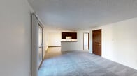 Located at 11020 16th Ave SW in Seattle, WA, this two-bedroom, two-bathroom unit is thoughtfully laid out across a single floor. The open living area features soft carpeting and a textured ceiling, with a sliding glass door that fills the space with natural light. A peninsula-style kitchen separates the cooking area from the living room and is equipped with dark walnut cabinetry, a tile backsplash, an electric range, and a full-size refrigerator, all set on tile flooring. Both bedrooms are carpeted and feature baseboard heating, windows for natural light, and dedicated closets. The primary bedroom offers a comfortable, well-proportioned space, while the second bedroom provides similarly clean and functional accommodations. Two full bathrooms serve the unit — one featuring a soaking tub and shower combination with stone-surround tile, a wood-toned vanity with a granite-style countertop, and tile flooring. A hallway connects the rooms for convenient flow throughout. The building exterior features mature trees and landscaped grounds with concrete walkways, staircase access, and a welcoming courtyard setting.