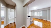 This compact yet efficiently designed 2-bedroom, 1-bathroom residence is laid out on a single floor, making excellent use of its space. A defining architectural feature throughout is the warm-toned parquet hardwood flooring, which adds timeless character and a polished finish to every room.

The kitchen stands out as a functional centerpiece, boasting granite countertops on a peninsula with an integrated sink and stainless steel dishwasher. White cabinetry, a stainless steel range, microwave, and refrigerator complete the space. The kitchen connects to the living area through a graceful arched passageway, lending a classic architectural charm to the open flow of the unit.

The primary bedroom is a comfortable, well-proportioned room featuring a ceiling fan with light fixture, a window with blinds for natural light control, and a closet. The second bedroom is a clean, bright space with the same attractive parquet flooring and a closet. Both rooms are finished in neutral gray tones, creating a calm and versatile atmosphere.

The hallways are connected by arched doorways that lend cohesion and style to the layout. The bathroom is finished in a clean, all-white palette with classic mosaic tile flooring and a full bathtub with shower.