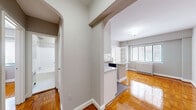 This compact yet efficiently designed 2-bedroom, 1-bathroom residence is laid out on a single floor, making excellent use of its space. A defining architectural feature throughout is the warm-toned parquet hardwood flooring, which adds timeless character and a polished finish to every room.

The kitchen stands out as a functional centerpiece, boasting granite countertops on a peninsula with an integrated sink and stainless steel dishwasher. White cabinetry, a stainless steel range, microwave, and refrigerator complete the space. The kitchen connects to the living area through a graceful arched passageway, lending a classic architectural charm to the open flow of the unit.

The primary bedroom is a comfortable, well-proportioned room featuring a ceiling fan with light fixture, a window with blinds for natural light control, and a closet. The second bedroom is a clean, bright space with the same attractive parquet flooring and a closet. Both rooms are finished in neutral gray tones, creating a calm and versatile atmosphere.

The hallways are connected by arched doorways that lend cohesion and style to the layout. The bathroom is finished in a clean, all-white palette with classic mosaic tile flooring and a full bathtub with shower.