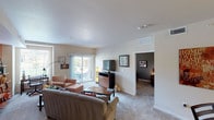 This single-floor residence offers a thoughtfully designed layout that balances comfort and functionality across its key living spaces. The living room serves as the central gathering area, featuring neutral carpet, smooth ceilings, and a bold terracotta accent wall adorned with open ladder shelving. Large sliding glass doors flood the space with natural light and provide direct access to a private outdoor patio, where views of surrounding greenery are visible. A secondary seating nook off the main living area provides additional versatility.

The kitchen is a standout feature, showcasing rich dark-wood cabinetry, granite countertops, and a full suite of stainless steel appliances including a range, microwave, dishwasher, and refrigerator. A tray ceiling with track lighting adds architectural interest, while a generous island with pendant lighting offers added prep and seating space. Wood-look flooring ties the kitchen and dining area together seamlessly.

The bedrooms are carpeted and well-proportioned, each offering a calm atmosphere with neutral tones and ample room for furnishings. The bathroom features wood-look flooring, dark vanity cabinetry, a tub-shower combination with mosaic tile accents, and built-in shelving for storage. Throughout, the design maintains a warm and cohesive aesthetic.
