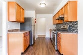 Located at 644 Silver Lake Scotchtown Rd in Middletown, NY, this single-floor unit offers a well-organized and functional layout across several distinct living areas. The kitchen is a standout feature, outfitted with warm wood cabinetry, granite-style countertops, stainless steel appliances including a gas range and refrigerator, and a mosaic tile backsplash. Hardwood-style flooring ties the kitchen together, creating a clean and practical cooking space. The bathroom features floor-to-ceiling neutral stone-look tile surrounding a full soaking tub, complemented by a window that introduces natural light. The living areas and bedrooms are finished with soft wall-to-wall carpeting and neutral-toned walls, creating a calm and versatile backdrop. Multiple windows throughout the unit allow natural light to fill the rooms, enhancing the open feel. Baseboard heating is present throughout the living spaces, ensuring consistent comfort year-round. The floor plan, as seen in the overhead model view, reveals a compact yet efficient arrangement with clear separation between the kitchen, living room, and bedroom areas, making good use of the available space.