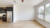 Located at 100 Nursery Lane in Fort Worth, Texas, this single-floor studio unit offers a well-designed layout that maximizes every square foot of its compact footprint. The open-concept interior features light wood-style flooring that runs continuously throughout the space, creating a cohesive and airy feel.

The kitchen is a standout feature, showcasing dark shaker-style cabinetry that extends to the ceiling for ample storage, light granite countertops, a subway tile backsplash, and a full suite of stainless steel appliances including a refrigerator, electric range, and built-in microwave. Track lighting and a modern pendant light add a contemporary touch to the kitchen and entry area.

The living area is bright and open, benefiting from natural light streaming through a window fitted with blinds. A ceiling fan provides additional comfort overhead, while crisp white walls keep the space feeling clean and versatile.

The bathroom is thoughtfully appointed with a dark-framed vanity mirror, granite countertop, undermount sink, and dark cabinetry that coordinates with the kitchen. A dedicated closet and a secondary access point with French doors further enhance the functionality of this efficiently designed unit.