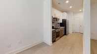 Located at 411 Flemington Rd in Chapel Hill, NC, this thoughtfully designed single-floor unit offers a clean, modern aesthetic with consistent light wood-tone flooring flowing seamlessly from room to room. The contemporary kitchen is outfitted with stainless steel appliances — including a range, microwave, dishwasher, and refrigerator — complemented by granite countertops, a tile backsplash, crisp white cabinetry, and recessed lighting, creating a functional yet stylish cooking space. The bedrooms are bright and well-proportioned, each featuring ceiling fans and access to dedicated closet space, including walk-in closets with built-in shelving for ample storage. Natural light filters through windows with blinds, adding to the airy, open feel of the living areas. The bathroom is finished with granite countertops atop dark cabinetry, a framed mirror, brushed nickel fixtures, and a tiled tub-shower combination, delivering a polished and cohesive look. Throughout the unit, crisp white walls and clean architectural lines contribute to a bright, minimalist ambiance. The layout, as revealed by the floor plan, is efficiently organized to maximize usable space while maintaining an open and comfortable flow between rooms.