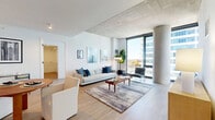 Located at 1717 South Michigan Avenue in Chicago's vibrant South Loop neighborhood, this well-appointed 2-bedroom, 2-bathroom residence offers a thoughtfully designed single-level layout with modern finishes throughout. The open-concept living room is anchored by dramatic floor-to-ceiling windows that flood the space with natural light and frame sweeping city views, complemented by exposed concrete ceilings and light hardwood flooring that carry throughout the unit. A dedicated entrance leads into a spacious hallway connecting all areas of the home seamlessly. The kitchen is outfitted with warm wood cabinetry, white quartz countertops, stainless steel appliances including a gas range, and a large island with bar seating — ideal for both cooking and casual dining. The primary bedroom enjoys generous proportions and direct access to expansive windows with city views, while the second bedroom also benefits from floor-to-ceiling glazing. Both bathrooms feature clean, contemporary finishes: one includes a glass-enclosed walk-in shower with marble-style tile and matte black fixtures, while the other offers a full soaking tub and shower combination. Four closets and an in-unit laundry room add practical convenience to this well-organized urban residence.