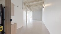 Located at 2348 S Santa Fe Ave in Los Angeles, this single-story space offers a generous, open-plan layout with a distinctly industrial-modern character. The architecture draws on warehouse-style design, featuring soaring ceilings with exposed wood beams, structural columns, and visible overhead piping — all finished in a clean, uniform white that amplifies the sense of openness and light throughout.

The main open area dominates the floor plan, providing a highly flexible, column-punctuated space with smooth, polished concrete floors that reflect light and enhance the airy ambiance. Track lighting mounted along the ceiling framework allows for adjustable illumination across the expansive floor. Industrial windows admit natural light, further brightening the all-white interior.

The kitchen is outfitted with light wood cabinetry — both upper and lower — paired with white countertops, a stainless steel sink with a matte black faucet, and stainless steel appliances including a refrigerator and dishwasher. The clean, Scandinavian-influenced design complements the overall minimalist aesthetic.

The bathroom features full white subway tile surrounding a soaking tub with an overhead shower, accented by matte black fixtures for a modern contrast. Together, these functional spaces support a wide range of creative, studio, or commercial uses.