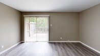 Located at 1400 Old Forge Dr in Little Rock, Arkansas, this two-story home offers three bedrooms and four bathrooms across two well-proportioned floors. The main level features a living room finished with wood-style luxury vinyl plank flooring in a warm gray tone, neutral taupe walls, and a sliding glass door with vertical blinds that opens to a private outdoor deck overlooking mature greenery — bringing in natural light and a sense of openness. The kitchen is efficiently laid out with light wood cabinetry, white countertops, and black appliances including a refrigerator, electric range, and dishwasher, all set on easy-care LVP flooring. The upper level houses the bedrooms, each carpeted in a neutral tone and equipped with ceiling fans and natural light from windows. The spacious primary bedroom includes a dedicated closet. The remaining bedrooms are well-sized and similarly appointed. The four bathrooms feature clean, functional designs with wood vanities, white countertops, and large mirrors. One bathroom notably features angled ceiling architecture. A dedicated closet and hallway complete the upper floor's layout, providing practical storage throughout.