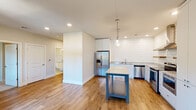 This thoughtfully designed one-bedroom, one-bathroom residence offers a functional and modern single-floor layout. The open-concept kitchen and living area serves as the heart of the home, featuring warm hardwood-style flooring, recessed lighting, and a clean, neutral color palette. The kitchen is well-appointed with white shaker cabinetry, granite countertops, stainless steel appliances including a French door refrigerator and range with hood, a subway tile shiplap accent wall, pendant lighting, and a freestanding island with a granite top — providing both additional prep space and a casual dining option. A window in the living area allows natural light to filter in, offering views of the surrounding neighborhood. The bedroom is a comfortable, carpeted retreat featuring a ceiling fan, multiple windows with roller shades that bring in natural light and outdoor views, and access to a walk-in closet outfitted with built-in shelving and hanging rods. The bathroom is finished with classic octagonal mosaic floor tile, subway tile surrounding the tub-shower combo, a granite-topped vanity, and a large mirror with overhead lighting — creating a bright, clean aesthetic throughout. This residence combines practical design with quality finishes for comfortable everyday living.