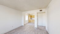 Located at 4401 E 29th St in Tucson, Arizona, this one-bedroom, one-bathroom residence offers a practical and efficient single-floor layout. The living room provides an open, airy feel with light wood-style flooring and a textured ceiling, flowing seamlessly into the kitchen through a wide archway. The kitchen is well-equipped with warm honey-toned wood cabinetry, white appliances including a refrigerator, electric range, microwave, and dishwasher, along with a single-basin sink and ample counter space. A hallway connects the main living areas to the private bedroom, which features the same light wood-style flooring, a window with vertical blinds that admits natural light, and direct access to a generously sized closet with dual hanging rods and built-in shelving. The bathroom includes a full tub-shower combination with chrome fixtures and towel bars. Throughout the unit, clean white walls and consistent flooring create a bright, cohesive atmosphere. The straightforward layout and functional design make this a practical Tucson residence.