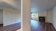 Located at 703 Stonebridge Way in Pleasant Hill, California, this single-story residence offers a well-organized layout with a blend of hardwood flooring and plush carpeting throughout. The living area is a welcoming focal point, featuring rich wood-tone flooring, a tile-surround fireplace, and a large window that frames views of the surrounding landscaping, filling the space with natural light. A ceiling fan adds both function and style to the adjoining area, which also includes a convenient pass-through window connecting to the kitchen. The kitchen is outfitted with white cabinetry, dark countertops, and white appliances including an electric range and an over-the-range microwave. Carpeted bedrooms provide a quiet retreat, each with windows offering pleasant outdoor views of mature trees and greenery. One bedroom features a sliding glass door that opens directly to a private balcony, extending the living space outdoors. The bathrooms are finished with tile flooring, white vanity cabinetry, and neutral countertops. One full bathroom includes a tub-shower combination with a high window for natural light. The overall ambiance is clean and bright, with a practical, comfortable layout suited to everyday living in the heart of Pleasant Hill.